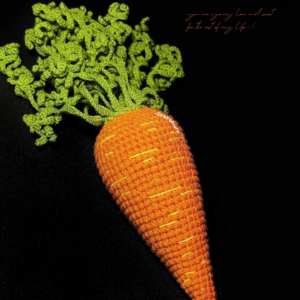 Crochet carrot amigurumi side view showing stitched surface details and green leaves